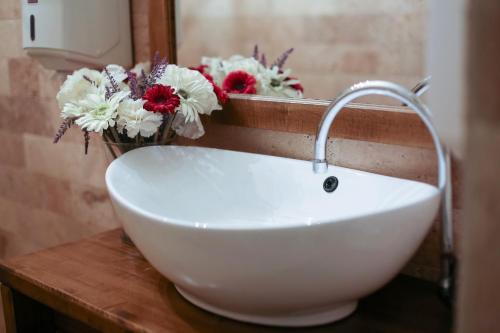 een witte wastafel met bloemen op een aanrecht in een badkamer bij Pensiune Restaurant La Cassa in Vişeu de Sus