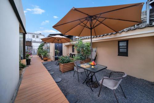 a patio with a table and chairs and an umbrella at Xi'an Travelling with Hotel South Gate in Xi'an