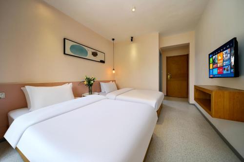 a hotel room with two beds and a flat screen tv at Xi'an Travelling with Hotel South Gate in Xi'an