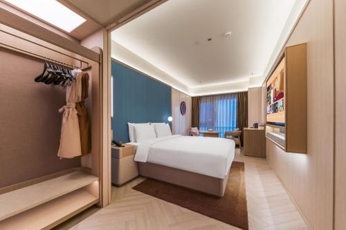 a hotel room with a bed and a desk at Orange Crystal Qingdao Taitung Pedestrian Street Hotel in Qingdao