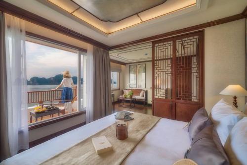 a living room with a view of a woman standing on a balcony at Heritage Line Ginger Cruise - Halong Bay & Lan Ha Bay in Ha Long