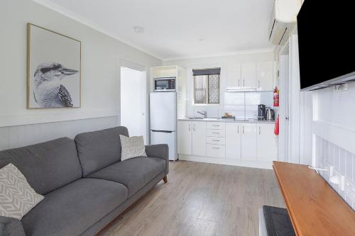 a living room with a couch and a kitchen at Reflections Seal Rocks - Holiday Park in Smiths Lake