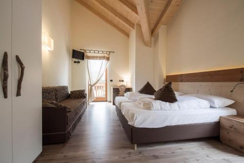 um quarto com 2 camas grandes e um sofá em Albergo Chalet Abete Rosso em Castello Tesino