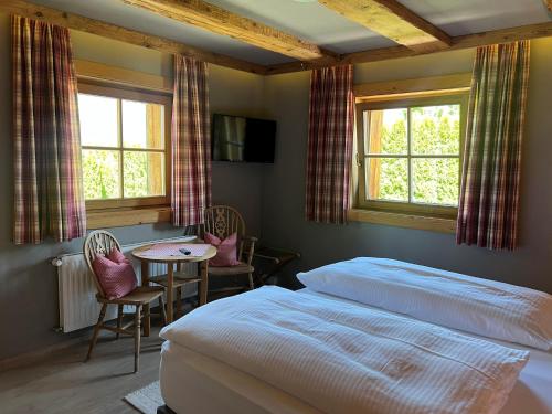 a bedroom with a bed and a table and two windows at Chalet in Ellmau near Ski Slopes in Ellmau