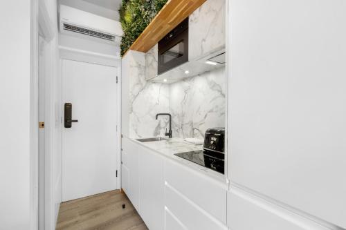 a kitchen with white cabinets and marble countertops at Brick Lane Base in London