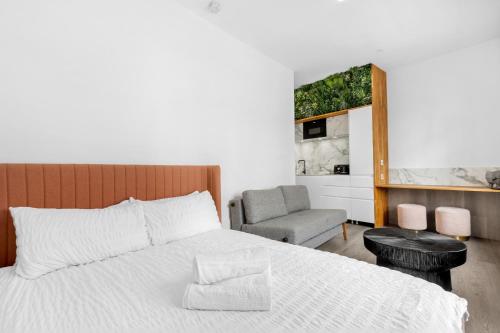 une chambre avec un lit blanc et une chaise dans l'établissement Brick Lane Base, à Londres