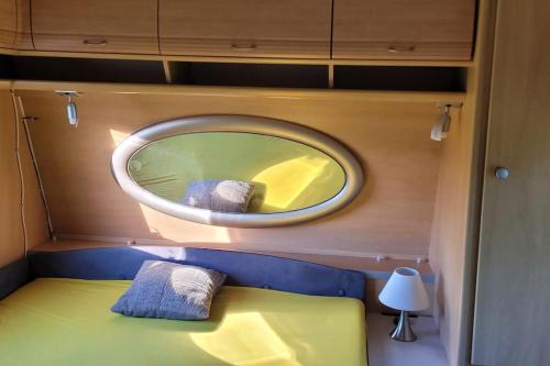 een ronde spiegel boven een bed in een kleine kamer bij Domek, caravaning nad jeziorem, Giże in Giże
