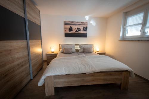 Un dormitorio con una cama grande con sábanas blancas. en Ferienwohnungen Kaiser, en Höchenschwand