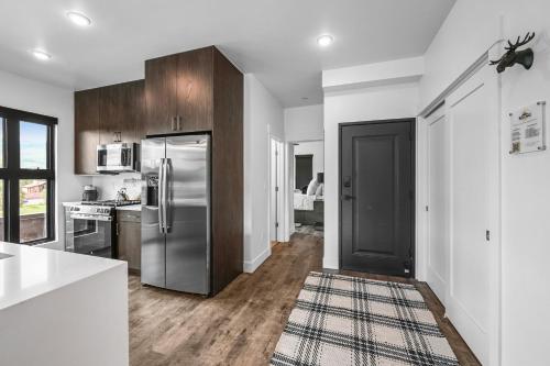 a kitchen with a stainless steel refrigerator and wooden cabinets at 4-Season Modern Mountain Penthouse with Private Hot Tub & Scenic Views in Silverthorne