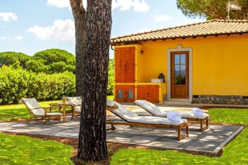 a patio with furniture and a tree in front of a house at Private Villa Among Pine Trees And Lavender in Marina di Grosseto