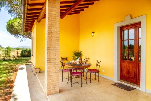 a patio with a table and chairs next to a yellow house at Private Villa Among Pine Trees And Lavender in Marina di Grosseto