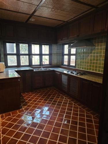 an empty kitchen with a tiled floor and windows at Insda Wellness Resort in Chiang Mai