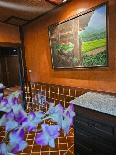 a painting on the wall of a kitchen with purple flowers at Insda Wellness Resort in Chiang Mai