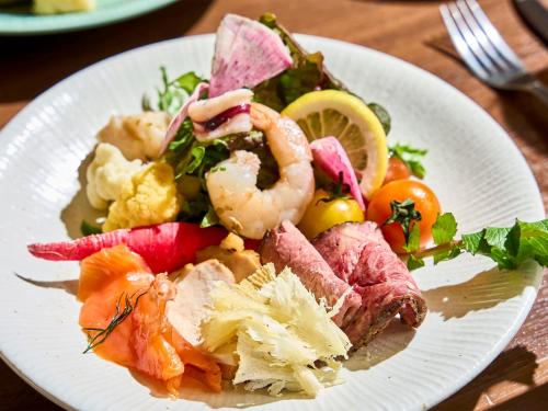 a plate of food with shrimp and vegetables on a table at Daiwa Roynet Hotel Hakata Reisen PREMIER in Fukuoka