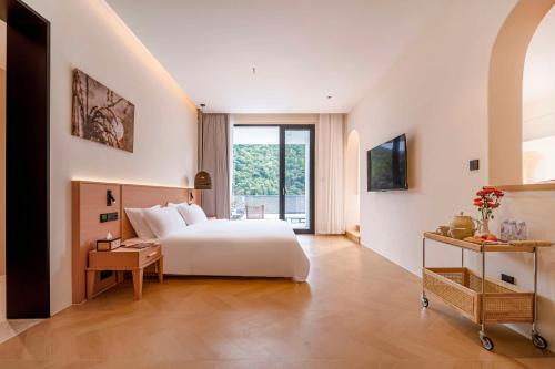a bedroom with a white bed and a window at Wuxing Qinglan Homestay in Houhong