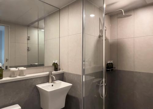 a bathroom with a sink and a glass shower at Ocean Suites Jeju Hotel in Jeju