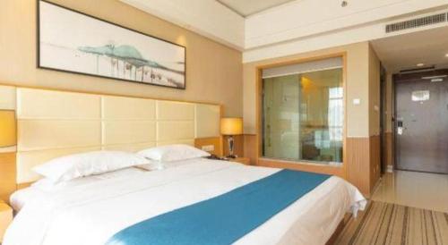 a bedroom with a large bed with a painting on the wall at The Prosperous City Hotel Weifang in Weifang