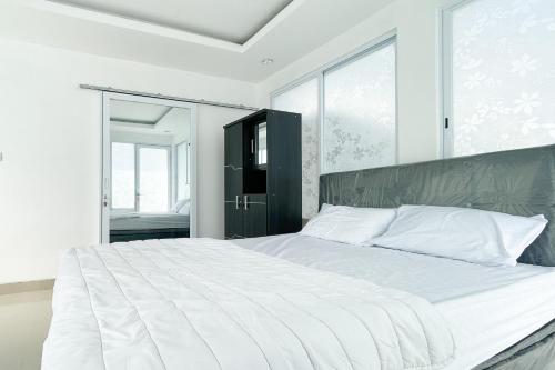 a white bedroom with a large bed with white sheets at RedDoorz near Politeknik Pariwisata Nusa Dua Bali in Nusa Dua