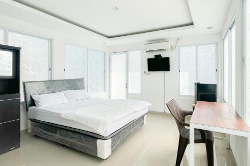 a bedroom with a bed and a desk and windows at RedDoorz near Politeknik Pariwisata Nusa Dua Bali in Nusa Dua