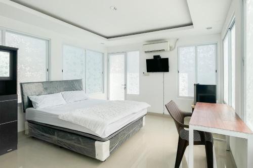 a bedroom with a bed and a desk and windows at RedDoorz near Politeknik Pariwisata Nusa Dua Bali in Nusa Dua