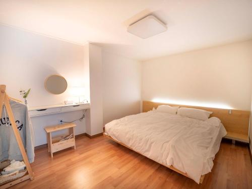 a white bedroom with a bed and a desk at Stay Cheonglim 靑林 in Seoul