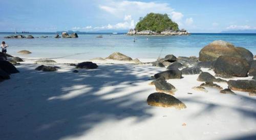a beach with rocks and the ocean and a island at The Key Hotel in Ko Lipe