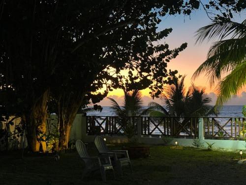 a sunset over the ocean with two chairs and trees at Casa Kiki in Omoa