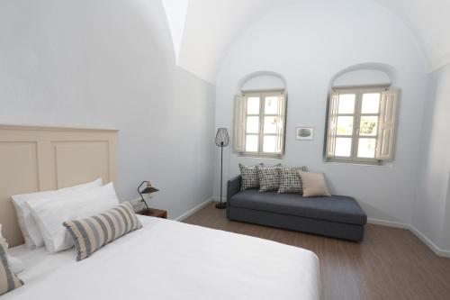 a white bedroom with a bed and a couch at Antique Mansion in Oia