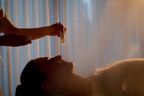 a woman laying on a bed with a person holding a toothbrush at 1 Hotel Melbourne in Melbourne