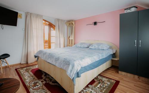 a bedroom with a bed in a room with pink walls at Casa Ilinca in Filioara