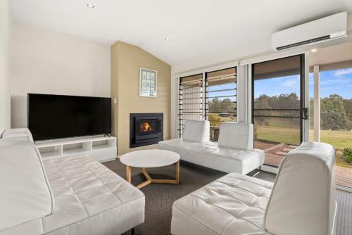 a living room with white furniture and a fireplace at H Boutique Hotel in Pokolbin