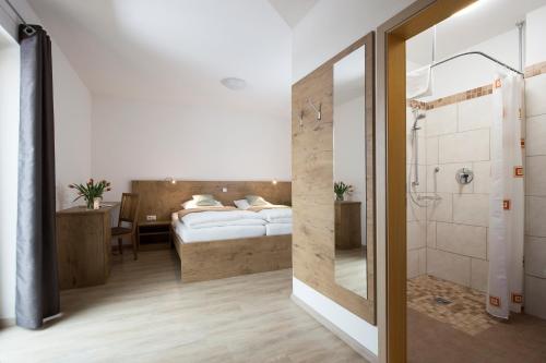 ein Schlafzimmer mit einem Bett und ein Badezimmer mit einer Dusche in der Unterkunft Fischhof Beer in Mitterteich