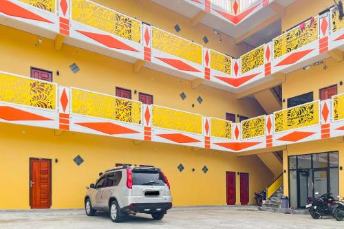 a white car parked in front of a yellow building at SANS Stay New Favour Pagaralam in Bumiagung