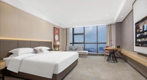 a bedroom with a large white bed and a large window at E-Cheng Hotel Yangjiang Baili Plaza in Yangjiang