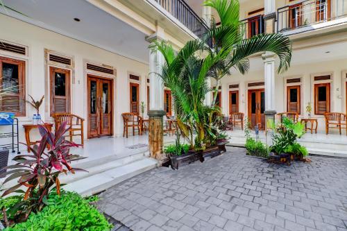 a courtyard of a building with chairs and palm trees at Collection O Bali near Beachwalk Shopping Center formerly Budget Door Legian Inn in Legian