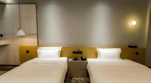 two beds sitting next to each other in a room at Borrman Hotel Jining High-tech Huangtun in Jining
