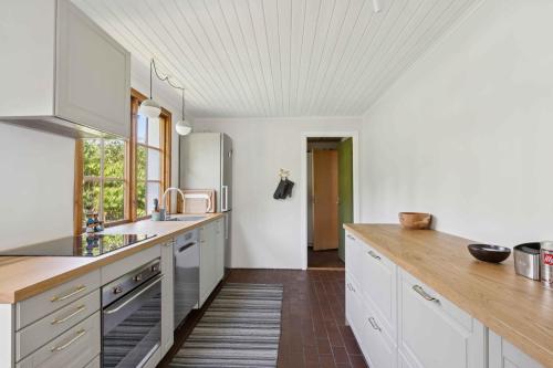 a kitchen with white cabinets and a wooden counter top at Holiday Bliss In Sandvig With Sea View in Sandvig