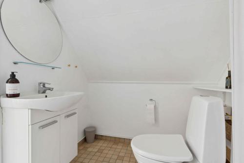 a white bathroom with a toilet and a sink at Holiday Bliss In Sandvig With Sea View in Sandvig