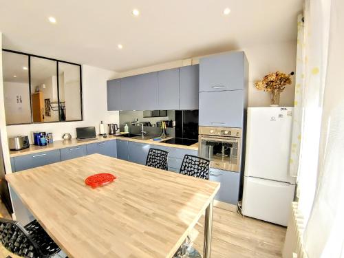 a kitchen with a wooden table and a refrigerator at Une halte, Proche Notre-Dame in Rodez