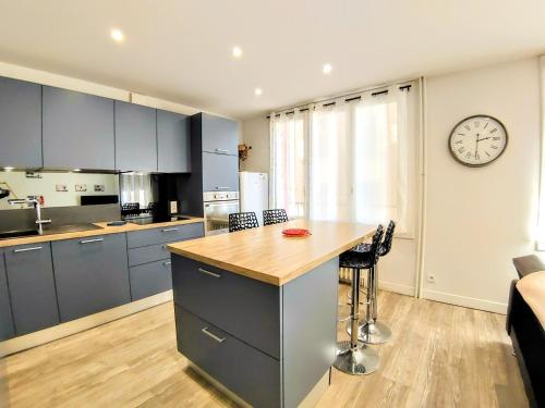a kitchen with blue cabinets and a clock on the wall at Une halte, Proche Notre-Dame in Rodez
