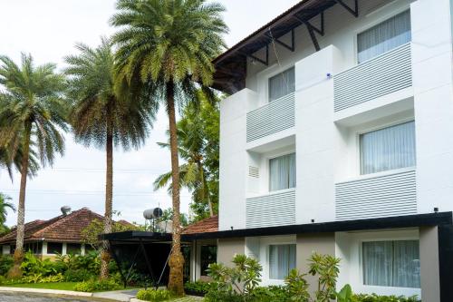 a building with palm trees in front of it at Hotel Riviera Garden in Cochin