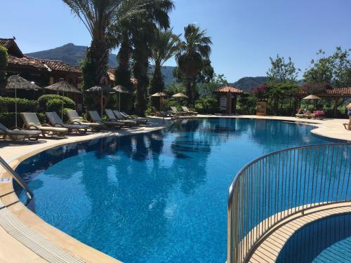 a large swimming pool with chairs and palm trees at Asur Hotel & Aparts & Villas in Dalyan
