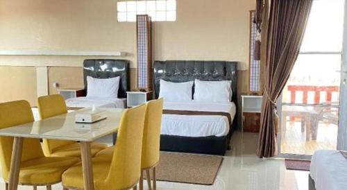 a hotel room with two beds and a table and chairs at Sunset Curly Bay Hotel & Resort in Tanjung Pinang 