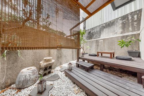 a patio with a wooden bench and some plants at IsShoNi house in Tainan