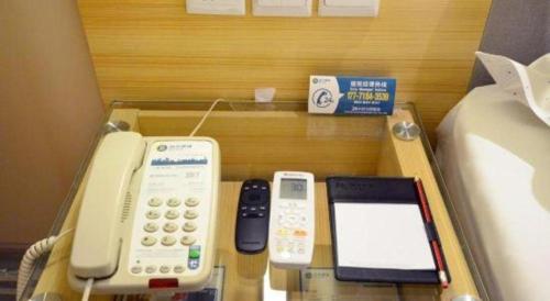 a table with a cell phone and other electronics on it at City Comfort Inn Hotel Wuhan Optics Valley Square Metro Station Zhongnan Minzu University in Wuhan