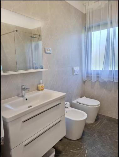 a white bathroom with a sink and a toilet at App Meri in Savudrija