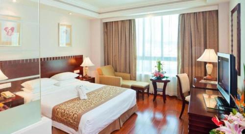 a hotel room with a bed and a television at Sanya Baohong Hotel in Sanya