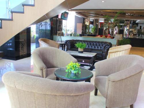 a lobby with chairs and a table with flowers on it at Hermes Palace Hotel Medan in Medan