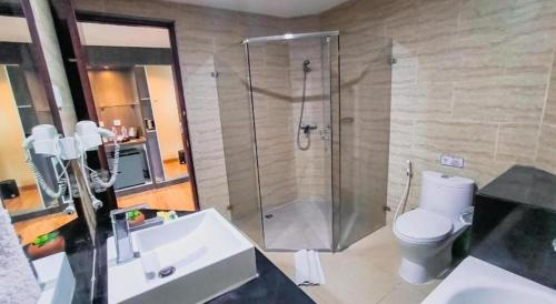 a bathroom with a shower and a toilet and a sink at Hermes Palace Hotel Medan in Medan