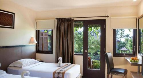 a hotel room with two beds and a desk with a table at Sambi Resort, Spa & Resto in Yogyakarta